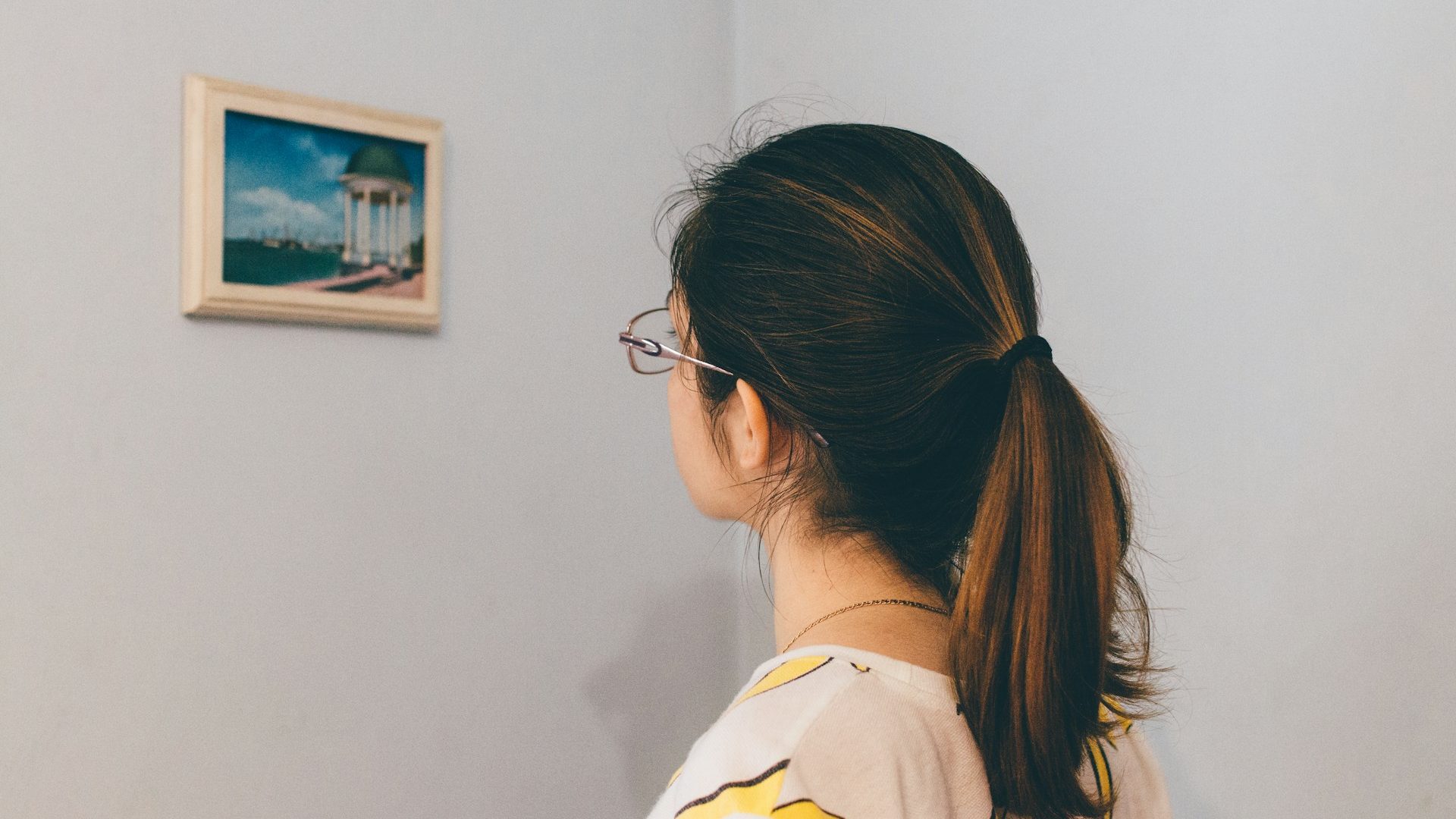 A lady looking at a hanging picture frame